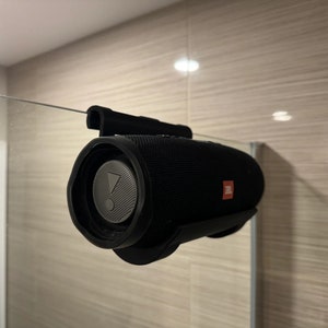 May include: A black waterproof Bluetooth speaker with a red JBL logo attached to a shower wall with a suction cup mount.