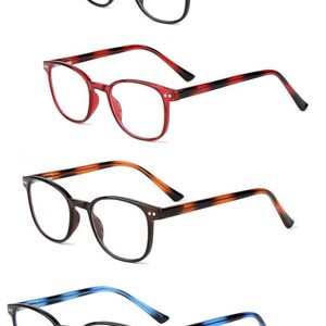 Può includere: Quattro paia di occhiali con lenti trasparenti. Le montature sono nere, rosse, marrone tartarugato e blu navy. Ogni paio ha una forma rettangolare arrotondata. Le aste degli occhiali sono a tinta unita o hanno un design sfumato.