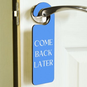 Peut inclure: Un porte-nom de porte bleu avec le texte "COME BACK LATER" en lettres blanches.