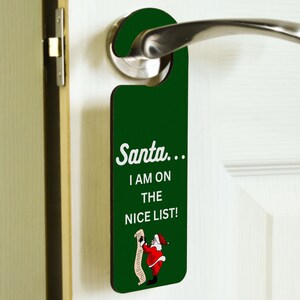 Puede incluir: Colgador de puerta verde con una ilustración blanca de Papá Noel y el texto "Santa... I am on the nice list!"