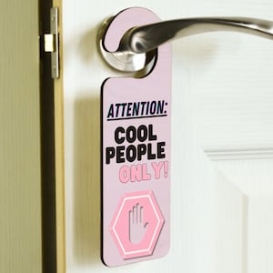 May include: Pink door hanger with the text "ATTENTION: COOL PEOPLE ONLY!" and a pink stop sign with a hand print.