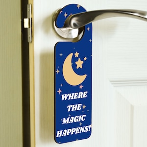 May include: A blue door hanger with a crescent moon and stars. The text on the hanger reads "Where the magic happens!"