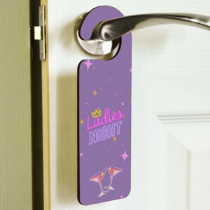 Könnte beinhalten: Lilafarbener Türhänger mit einem pinkfarbenen Neon-Schild mit der Aufschrift "Ladies Night" und zwei pinkfarbenen Martini-Gläsern. Der Hintergrund ist ein lilafarbenes und pinkfarbenes Sternenmuster.