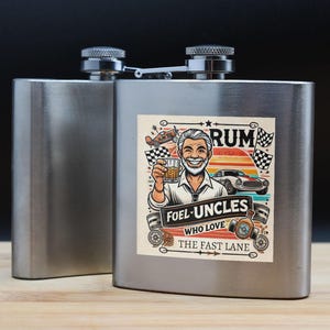 May include: A silver flask with a colorful sticker featuring a cartoon man holding a glass of rum. The sticker says "Fuel Uncles Who Love The Fast Lane".