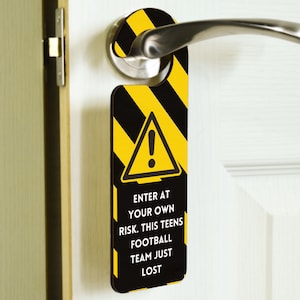 May include: A black and yellow door hanger with a warning sign and the text "Enter at your own risk. This teens football team just lost."