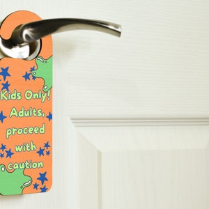 Może przedstawiać: Pomarańczowy i zielony wieszak na drzwi z napisem "Kids Only! Adults, proceed with caution" i niebieskimi gwiazdami.