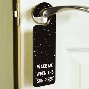 May include: Black door hanger with white polka dots and the text "Wake me when the sun rises".