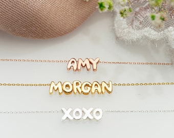May include: Three gold necklaces with different names on them. The top necklace says "AMY" in rose gold, the middle necklace says "MORGAN" in yellow gold, and the bottom necklace says "XOXO" in silver.