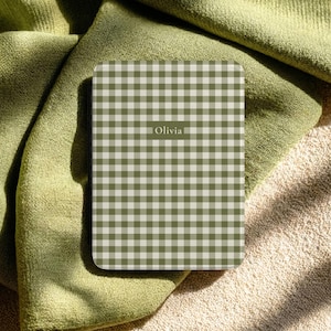 May include: A rectangular e-reader case featuring a sage green and white gingham check pattern. The center of the case displays the name Olivia in a white, sans-serif font. The case has a smooth, flat surface with rounded corners.