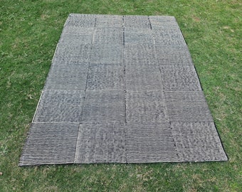 May include: A rectangular area rug featuring a patchwork design composed of multiple square panels. Each square displays a distinct black and white woven texture, creating a grid pattern across the entire surface of the floor covering.