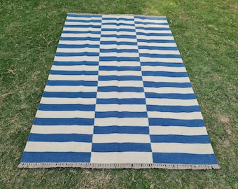 May include: A rectangular area rug featuring a repeating pattern of horizontal blue and off-white stripes. The design includes a central vertical panel of stripes flanked by two side sections with horizontal stripes. The rug has short fringe at both ends.