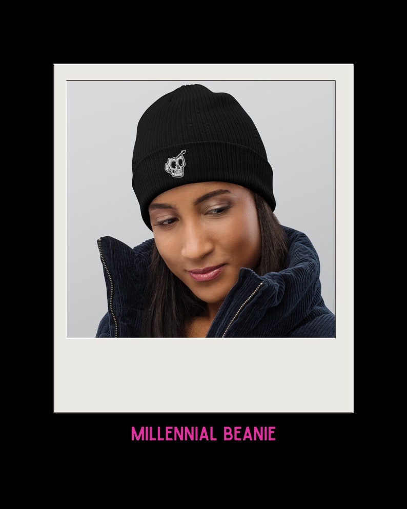 Op de afbeelding: Zwarte beanie met een wit schedel- en kruisbeenderontwerp. De beanie is geribbeld en heeft een omslagmanchet. De tekst "MILLENNIAL BEANIE" is onder de afbeelding gedrukt.