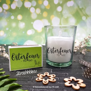 May include: A green matchbox with the text "Osterfeuer - TO GO -" and the word "Streichholzer" below. A small glass jar with a white candle inside and the text "Osterfeuer TO GO" on the side.
