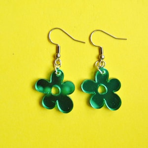 Puede incluir: Un par de pendientes de flor verde con espejo y ganchos plateados.