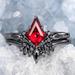 May include: A black ring with a large, red, triangular gemstone surrounded by smaller black gemstones. The ring is set on a white, icy background.
