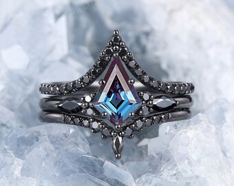 May include: A black ring set with a blue and purple gemstone in a geometric shape. The ring is set on a bed of white crystals.