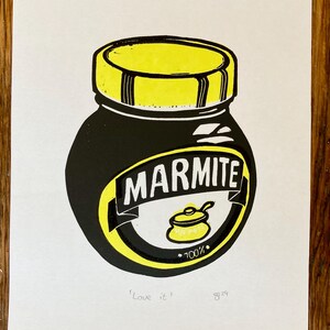 May include: A black and yellow illustration of a jar of Marmite spread. The jar has a yellow lid and a label that says "Marmite" in black letters. The label also has a small yellow pot with a spoon inside and the text "100%". The text "Love it" and the number "829" are written below the jar.