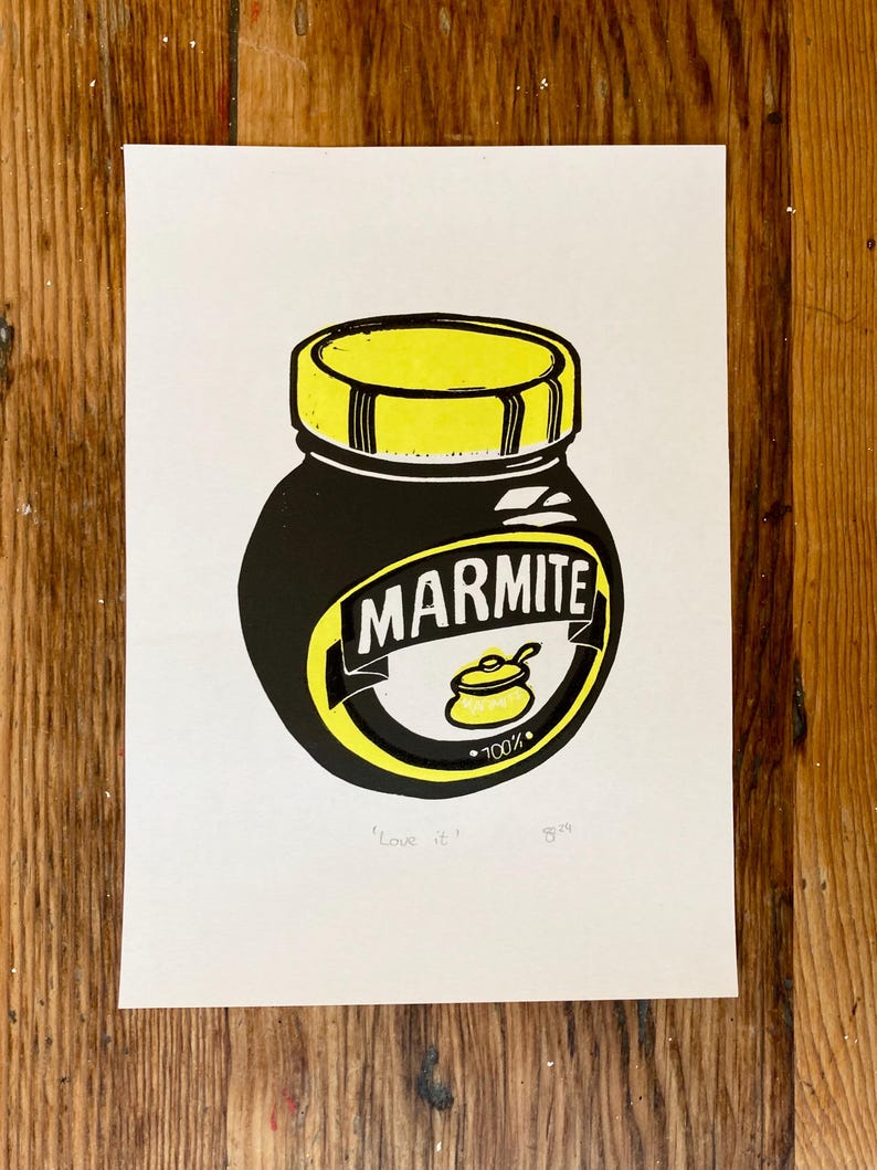 May include: A black and yellow illustration of a Marmite jar with the text "Marmite" and "100%" on the label. The text "Love it" is written below the jar.