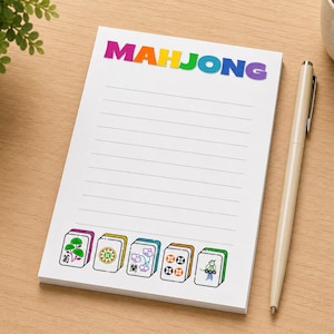 May include: A white notepad with horizontal lines featuring the word MAHJONG in rainbow-colored letters at the top. The bottom of the page displays five colorful mahjong tiles with various illustrations including a tree, a flower, and a bird.