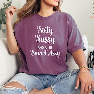 a woman sitting on a couch wearing a shirt that says sexy sasy and a