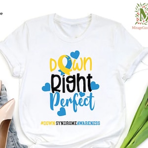 May include: White t-shirt with the text "Down Right Perfect" in black and yellow lettering with blue hearts surrounding the text. The hashtag #DownSyndromeAwareness is printed below the text.