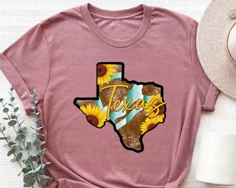 May include: A heather mauve t-shirt with a graphic of the state of Texas with sunflowers and the word "Texas" printed on it.