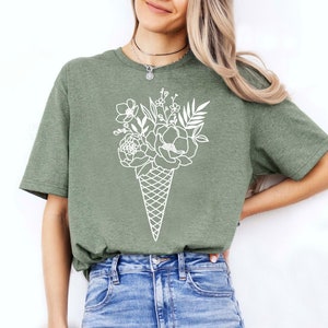a woman wearing a green t - shirt and ripped jeans