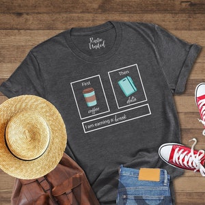 May include: A dark heather grey t-shirt with a white graphic design. The graphic features two boxes, one with a cup of coffee and the text "coffee" and the other with a phone and the text "data". The text "I am earning a break" is below the boxes.