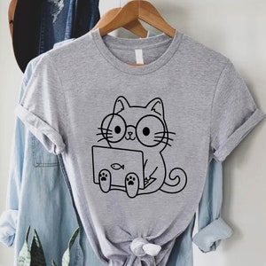 May include: A gray t-shirt with a black line drawing of a cat wearing glasses and using a laptop. The cat has a small fish icon on the laptop screen.