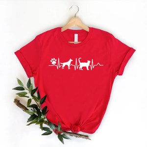 May include: Red t-shirt with a white paw print and heartbeat graphic with a dog and cat silhouette.