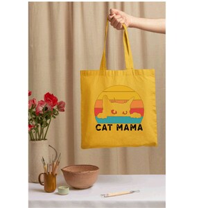 a person holding a yellow bag with a cat mama on it