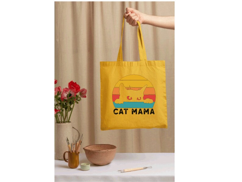 a person holding a yellow bag with a cat mama on it