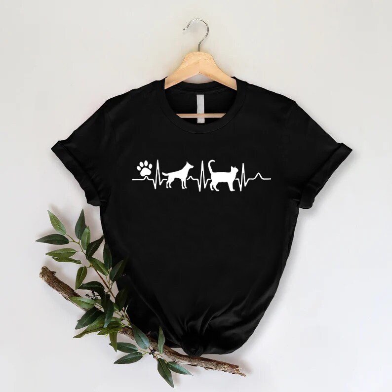 May include: Black t-shirt with a white paw print and heartbeat graphic featuring a dog and cat silhouette.