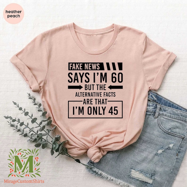 a pink shirt that says fake news says i'm 60 but the alternative fact