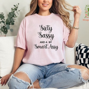 a woman sitting on a couch wearing a pink shirt