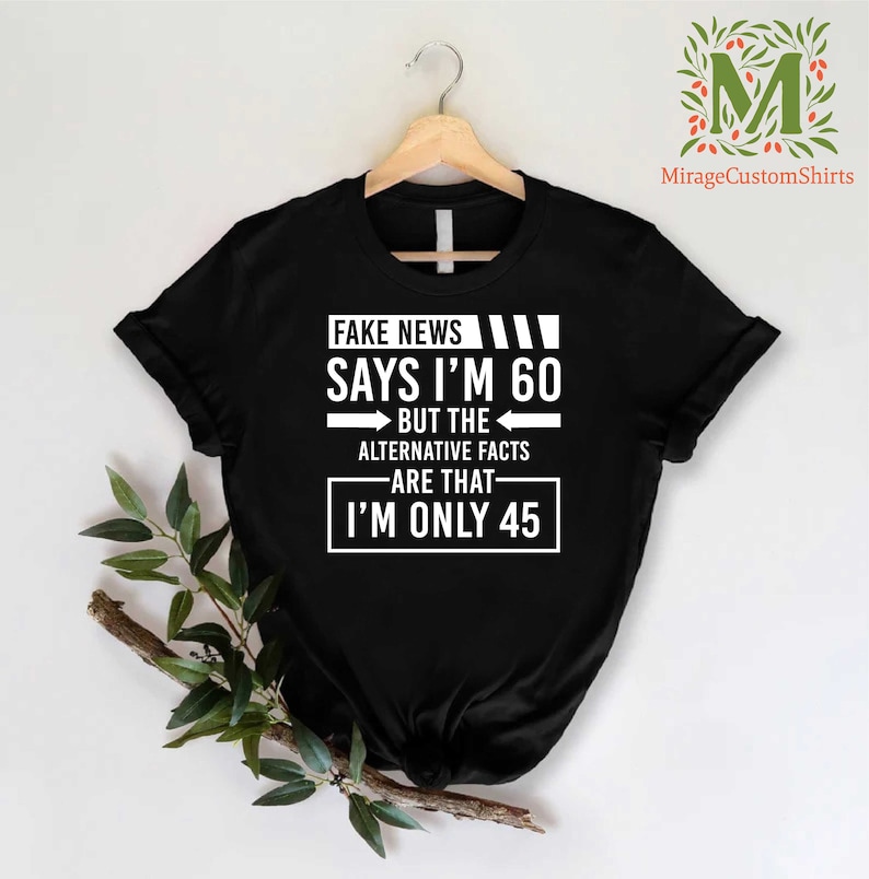 a black t - shirt that says fake news says i'm 60 but the