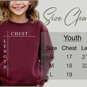 a young girl wearing a maroon sweatshirt with the measurements for her size
