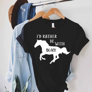 May include: Black t-shirt with white text that reads "I'd rather be with black" and a white silhouette of a horse.