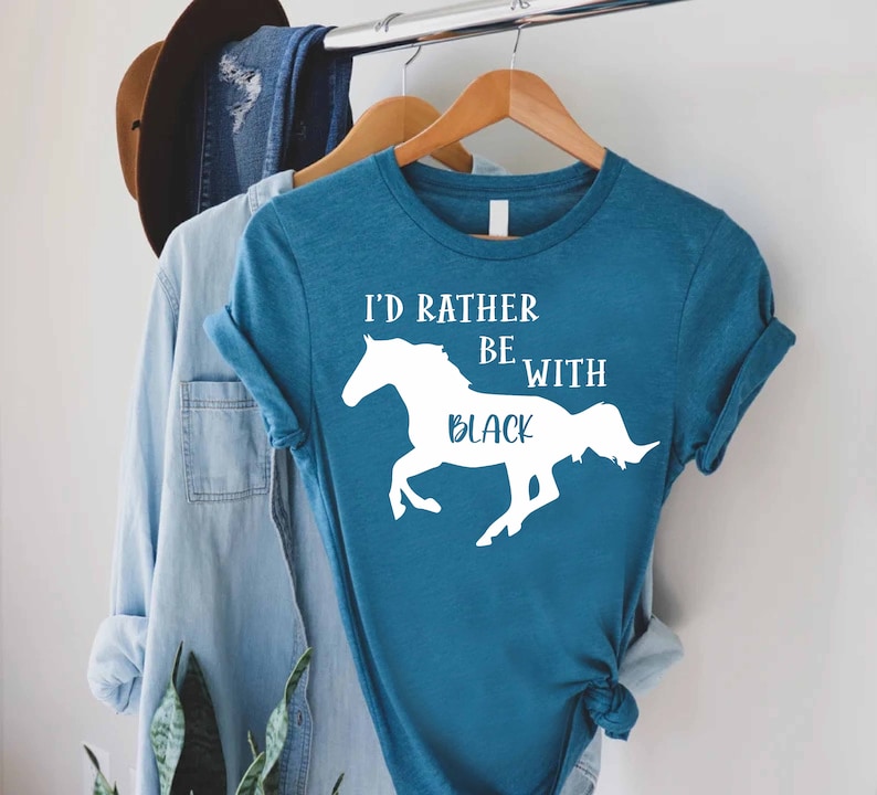 May include: A teal blue t-shirt with a white silhouette of a horse and the text "I'd rather be with black".