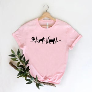 May include: Pink t-shirt with a black paw print and heartbeat graphic with a dog and cat silhouette.