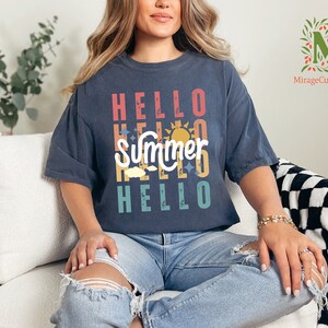 a woman sitting on a couch wearing a t - shirt that says hello summer hello