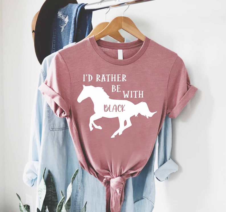 May include: A pink t-shirt with a white silhouette of a horse and the text "I'd rather be with black".