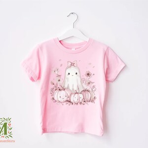 a pink t - shirt with a picture of a cat and pumpkins on it