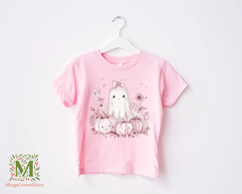 a pink t - shirt with a picture of a cat and pumpkins on it
