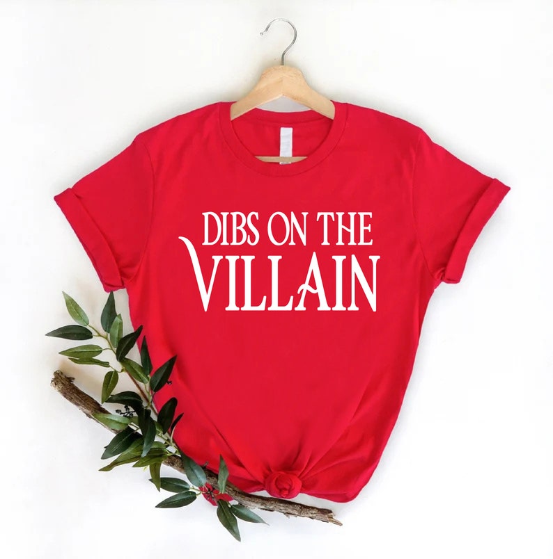 May include: Red t-shirt with white text that reads "Dibs on the Villain".