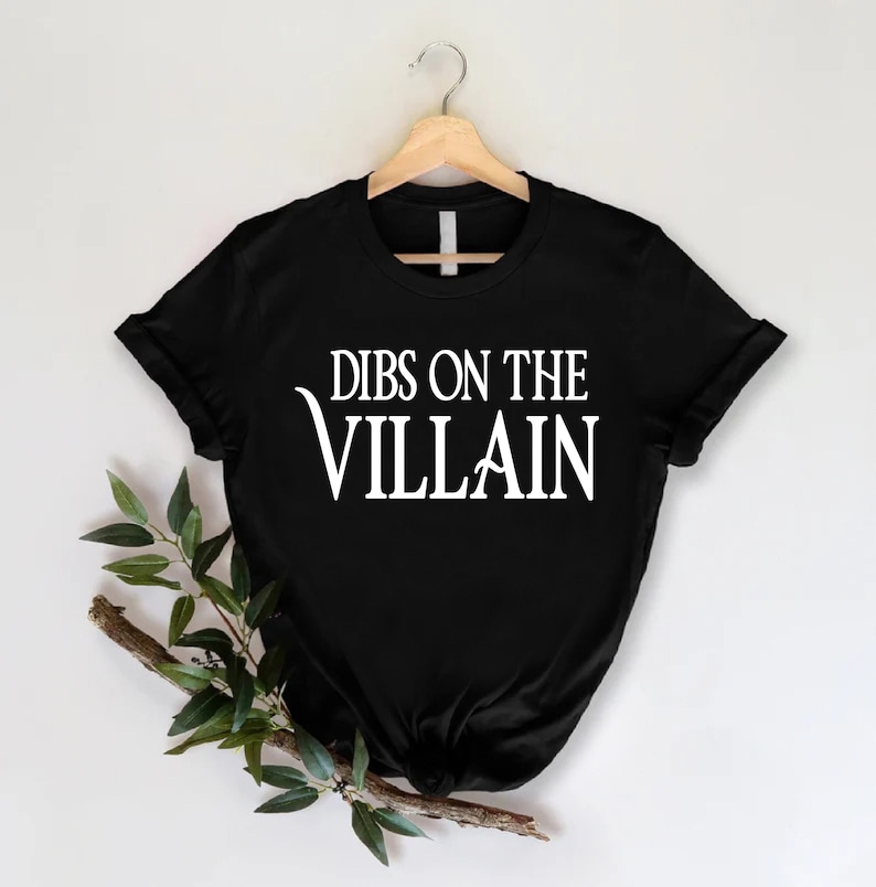 May include: Black t-shirt with white text that reads "Dibs on the Villain".