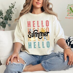 a woman sitting on a white couch wearing a t - shirt that says hello summer