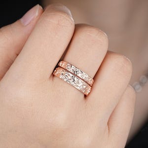 May include: Two gold rings with a floral design. The rings are stacked on top of each other.