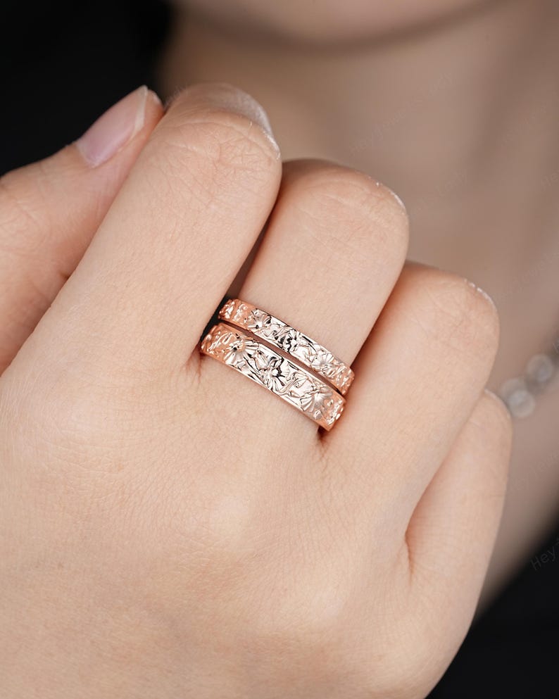 May include: Two gold rings with a floral design. The rings are stacked on top of each other.