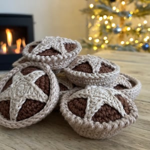 Puede incluir: Una pila de mini tartas de crochet marrones y beige con un diseño de estrella en la parte superior. Las tartas están apiladas sobre una superficie de madera.